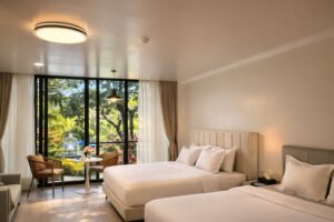 Spacious hotel in Cavite room with two beds and large windows overlooking a garden.
