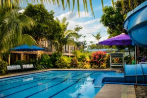 Outdoor swimming pool at a hotel in Cavite with tropical landscaping and a waterslide