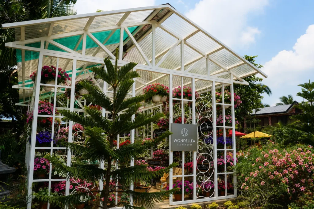 Beautiful white flower shop greenhouse surrounded by colorful blooms at Wondellea Cafe & Resort, Silang Cavite, offering a scenic garden experience and a wide selection of flowering plants.