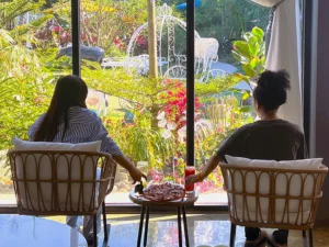 Guests relaxing by a garden view at a coffee shop near me open with comfortable seating