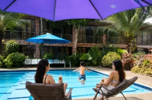 Families relaxing by pool at an event place in Cavite with pool and tropical garden.
