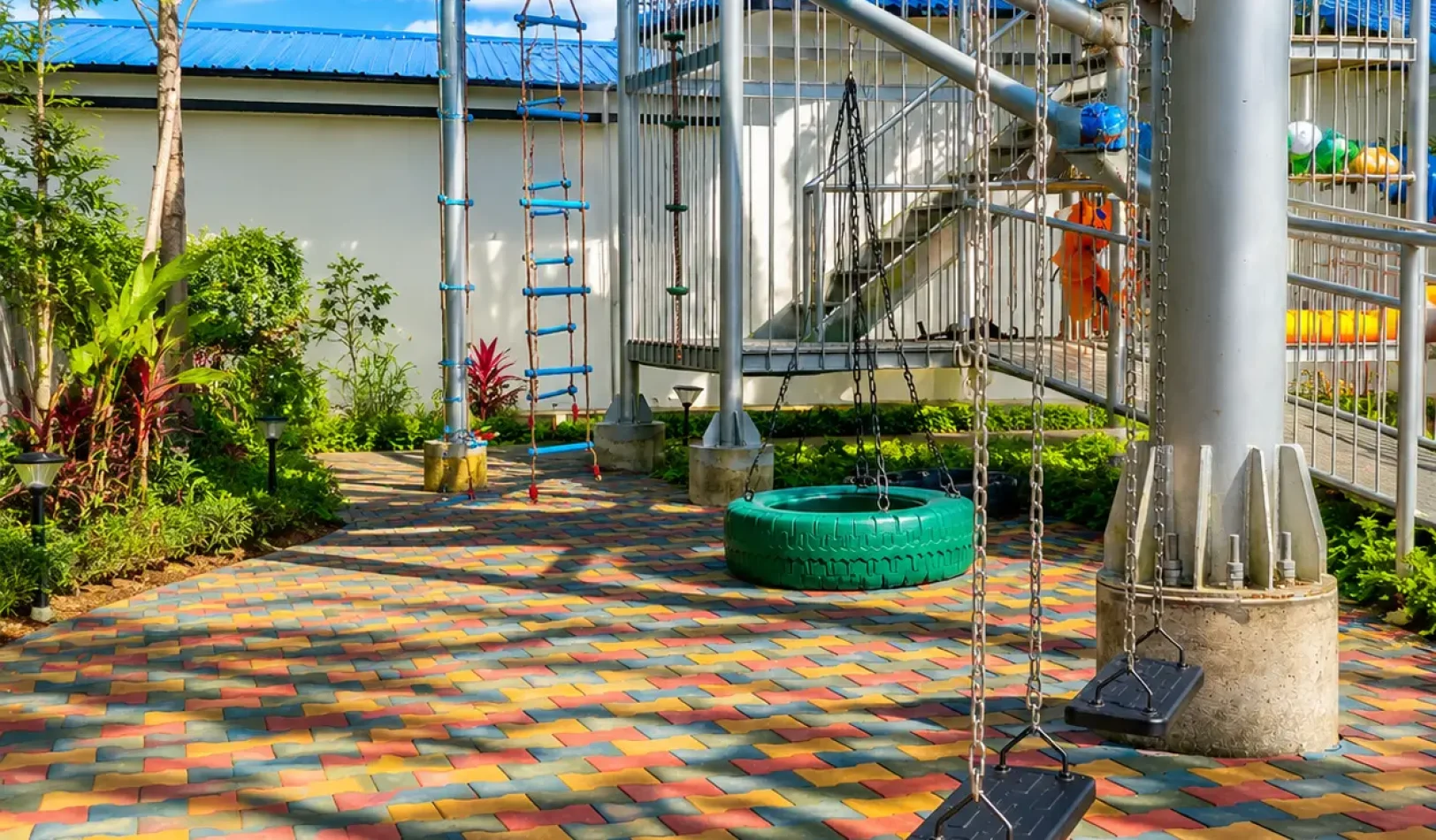 Outdoor play area with swings and climbing ladders on colorful brick paving at Wondellea