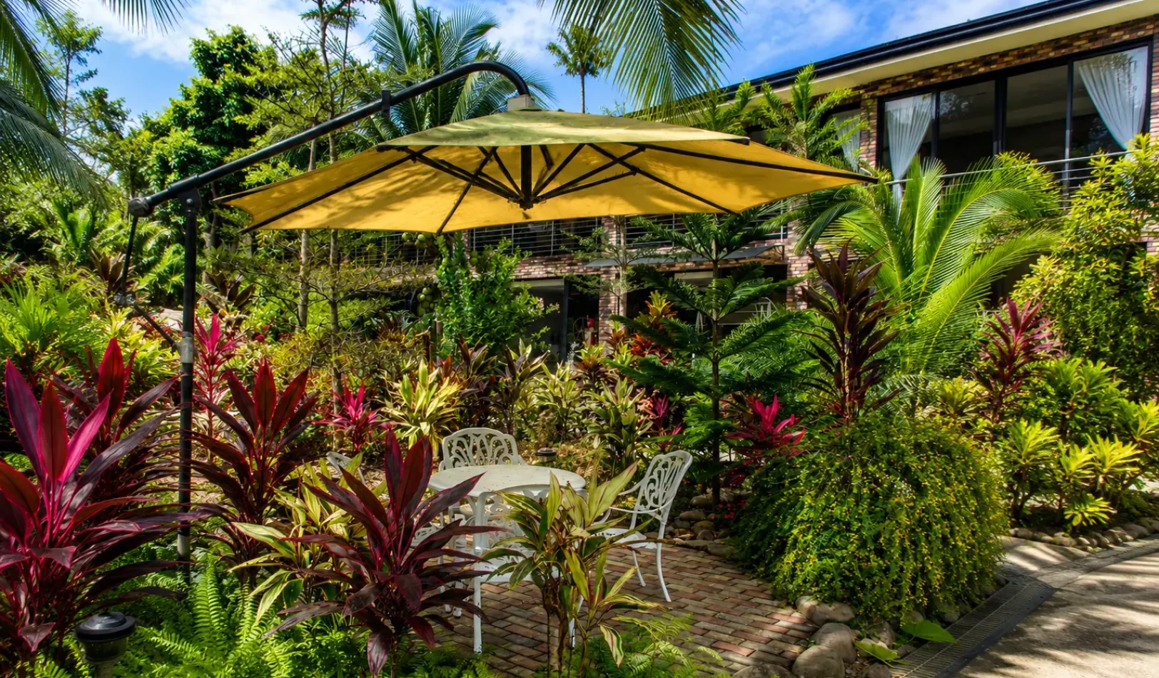 A white garden swing bench surrounded by lush plants and trees in the peaceful outdoor area at Wondellea