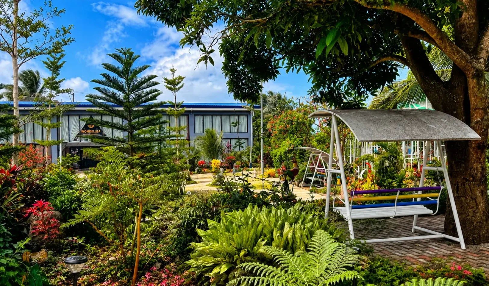 An elegant garden seating setup under a red umbrella featuring a giraffe statue in the outdoor area of Wondellea