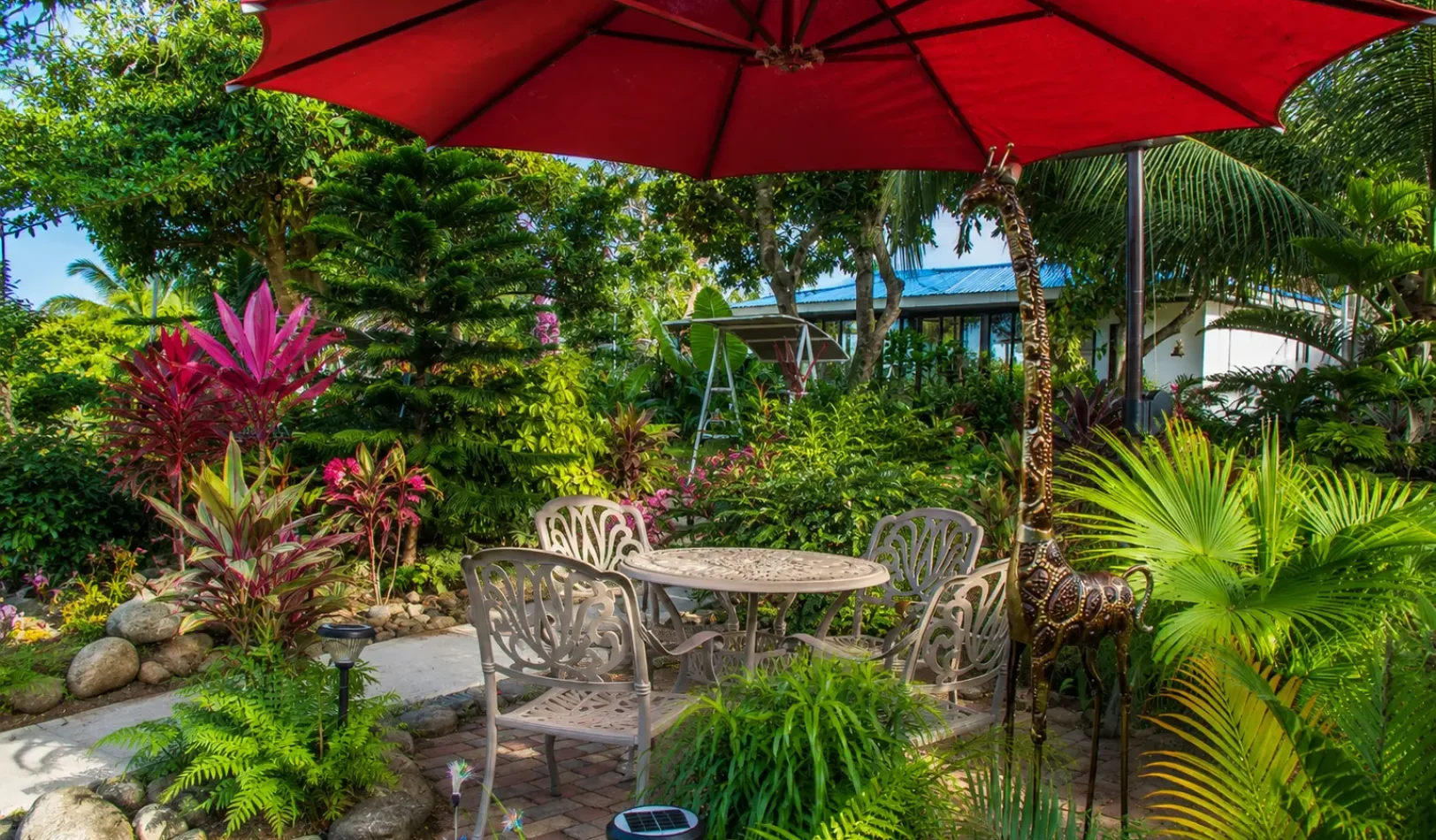 A beautiful patio table with white vintage chairs under a large umbrella in the outdoor area of Wondellea